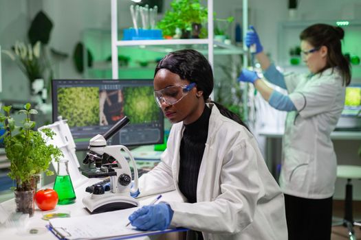 African biochemistry doctor examining chemical test using microscope