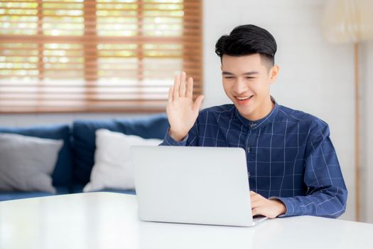 Young asian business man using laptop computer for video call online hello and communicate work from home, male conference with notebook and say hi, social distancing, communication concept.