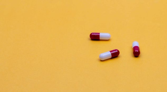 Red-white antibiotic capsule pills on yellow background. Prescription drug. Antibiotic drug resistance concept. Pharmaceutical industry. Pharmaceutics. Pharmacy product. Pharmacy drugstore banner.