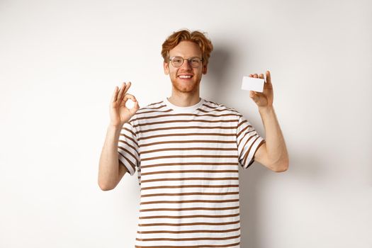 Shopping and finance concept. Satisfied male bank client showing OK sign and plastic credit card, smiling happy at camera.