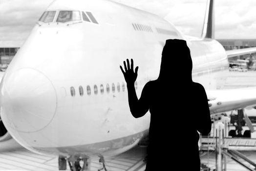 Black woman silhouette looking to aircraft in the airport hall- missed or cancelled flight concept.