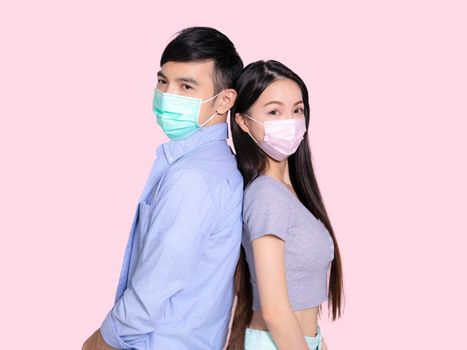 Young couple standing and wearing medical mask .isolated on pink background.