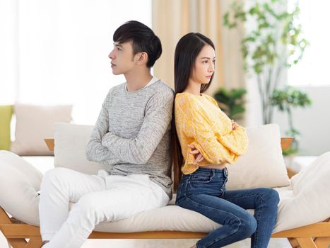 Young couple being in quarrel and not talking.Sitting in living room.