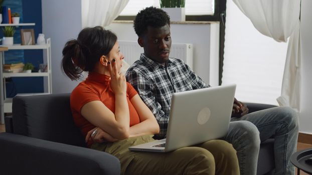 Married couple of interracial partners looking at laptop