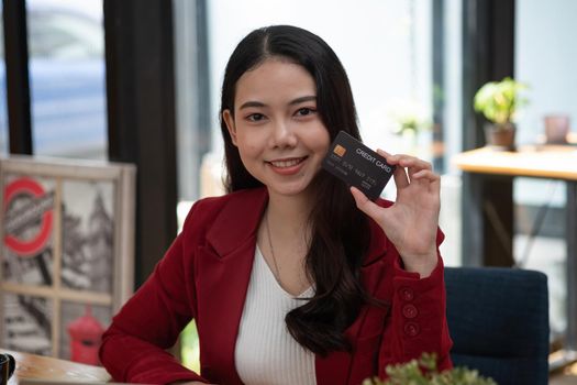 Charming asian woman showing credit card looking on camera. Online banking shopping concept