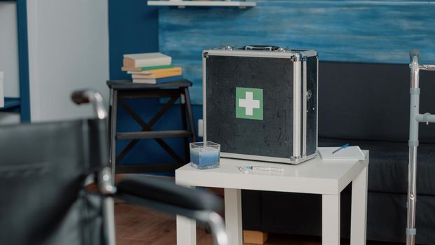 Close up of medical briefcase filled with healthcare equipment and tools for treatment and assistance on table. Suitcase with rehabilitation objects for wellness in nursing home.