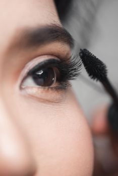 Woman applying mascara using eyelash wand