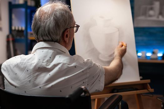 Senior artist with handicap creating vase drawing on canvas