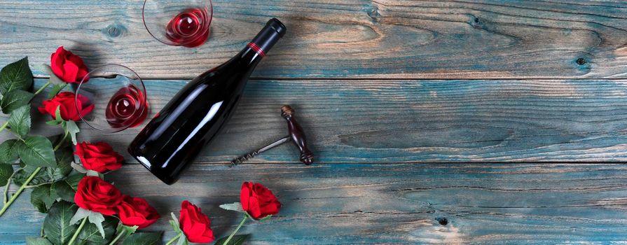 Valentines day celebration with roses and red wine on faded blue wood 