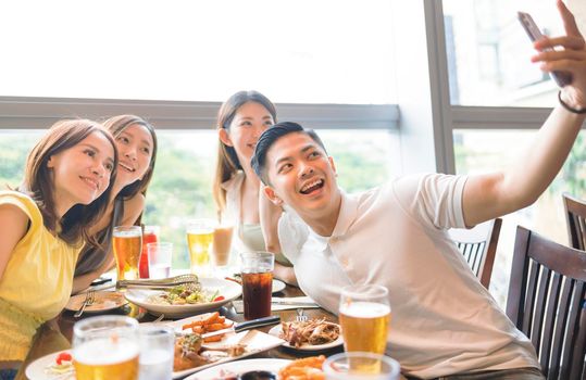 Happy young  group sitting in  restaurant and taking  selfie