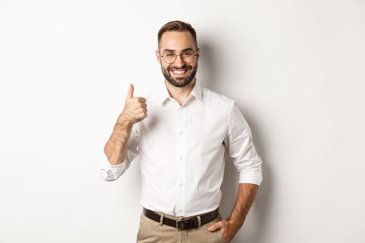 Satisfied successful boss showing thumb up, approve and praise good work, standing over white background