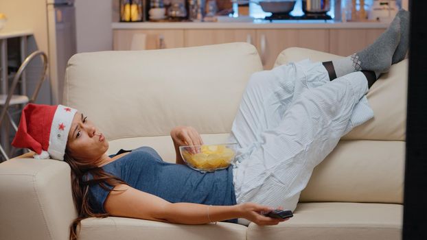 Unhappy woman watching television alone on christmas eve