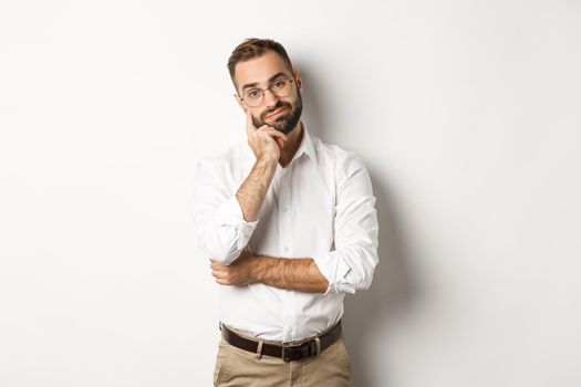 Unamused bearded man in glasses looking displeased at camera, standing moody over white background
