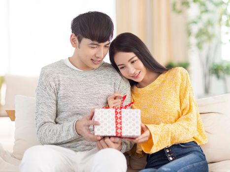 Young couple sharing gift in the living room.