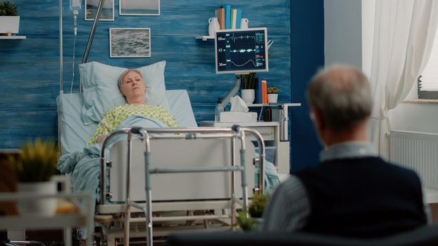 Senior woman laying in hospital bed at nursing facility