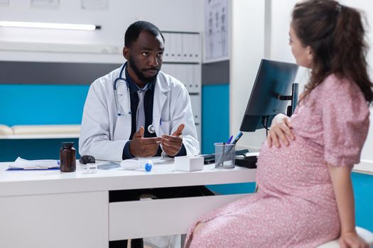 Woman with pregnancy discussing with specialist about medical care