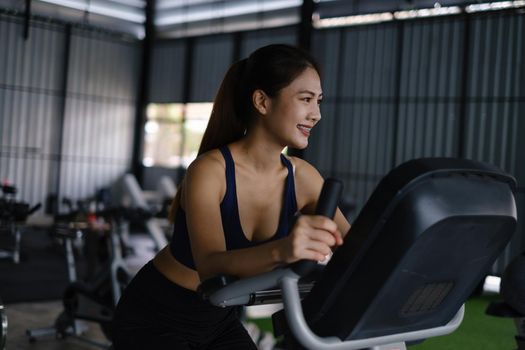 Happy young woman smiling and working out with sport biking fitness at class against fitness interface.