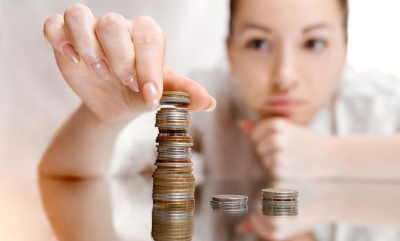 A thoughtful woman shifts coins from the pile to the pile. There's a coin tower.