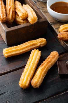 Tasty churros with chocolate caramel sauce, on old dark wooden table background