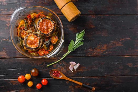 Portobello mushrooms,baked with cheddar cheese, cherry tomatoes and sage in glass pot on old wooden background top view space for text.