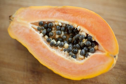 Fresh organic ripe papaya fruit cut in half on a wooden board. Exotic fruits, healthy eating concept