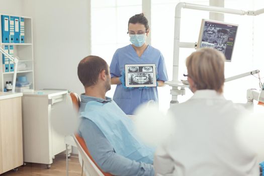 Orthodontist nurse holding digital tablet with tooth radiography on screen