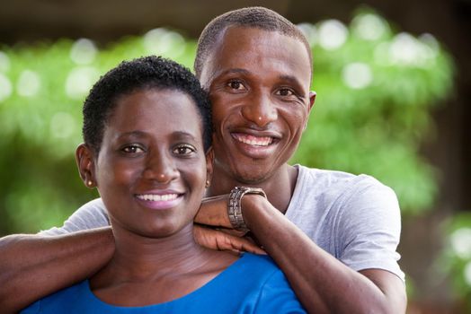 young african couple standing up looking at camera laughing.