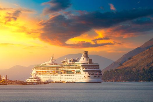 Cruise ship at harbor. Beautiful large white ship at sunset. Colorful landscape with cruiser in marina bay, sea, colorful sky. Luxury cruise ship leaving port at sunset.