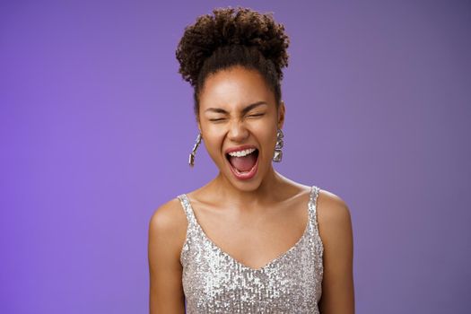 Joyful good-looking african-american stylish young woman in silver evening dress close eyes yawning sleepy tired party all night standing amused blue background wanna sleep