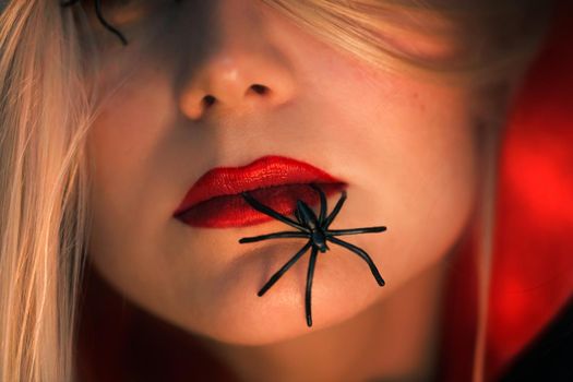 Halloween Makeover Fashion Ideas. Beautiful Female Face with Spiders. Holiday Makeup. Bright Red Lipstick. Blond Hair. Girl Model. Lips Closeup.