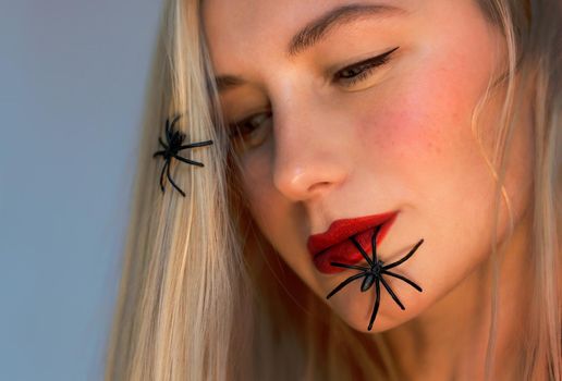 Halloween Makeover Fashion Ideas. Beautiful Female Face with Spiders. Holiday Makeup. Bright Red Lipstick. Blond Hair. Girl Model. Lips Closeup.