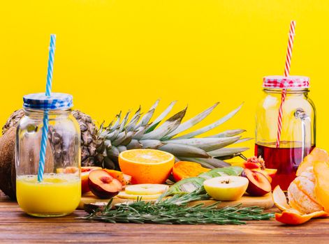 fruits rosemary juice mason jar chopping board against yellow backdrop. High quality photo