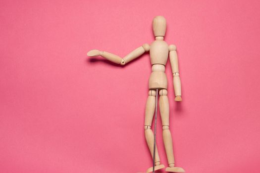 wooden mannequin on pink background posing close-up