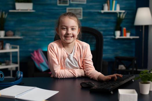 Portrait of smiling schoolkid sitting at desk table in living room