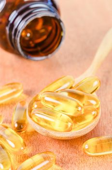 fish oil capsules in wooden spoon.
