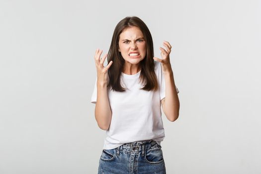 Mad and furious brunette girl clenching hands and grimacing angry