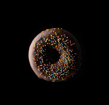 chocolate donuts with multicolored sprinkles levitate on a black background