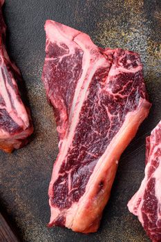 Raw fresh beef T bone steak, on old dark rustic background, top view flat lay