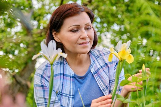 Portrait of 40s woman enjoying iris flowers in a spring garden