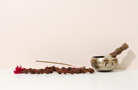 copper singing bowl and wooden clapper on a white table. Musical instrument for meditation, relaxation, various medical practices related to biorhythms, normalization of mental health
