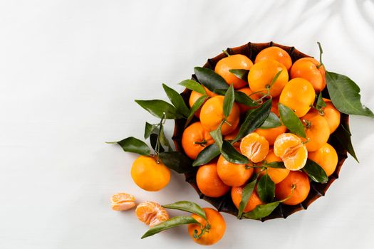 Fresh mandarin oranges fruit or tangerines with leaves in wooden box, top view