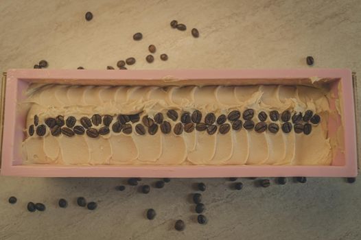 Preparation of handmade soap. The base for soap in silicone form, decorated with coffee beans. Top view, horizontal composition, copy space, color toning