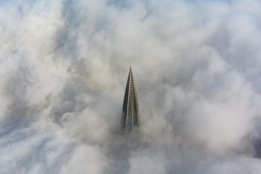 Russia, St. Petersburg, 14 October 2021: The top of the tallest skyscraper in Europe above the clouds, the building of the Gazprom oil company, the spire of a metal and glass structure