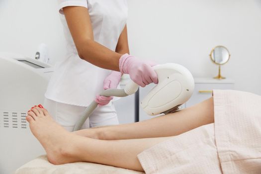 Partial view of woman receiving laser hair removal epilation on leg in a salon