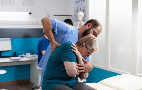 Osteopathic assistant cracking back and shoulder bones
