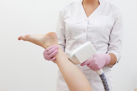 Partial view of woman receiving laser hair removal epilation on leg in a salon
