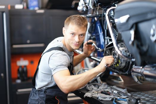 Male mechanic in a garage repairing a motorcycle