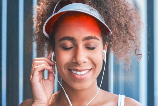 Young woman in tennis visor putting on earphones free style on t