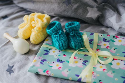 Knitted booties for a small child and a gift tied with a ribbon.