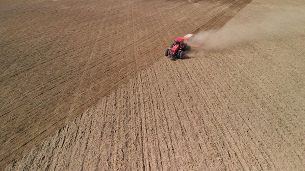 Tractor cultivates arid farmland in a desolate prairie